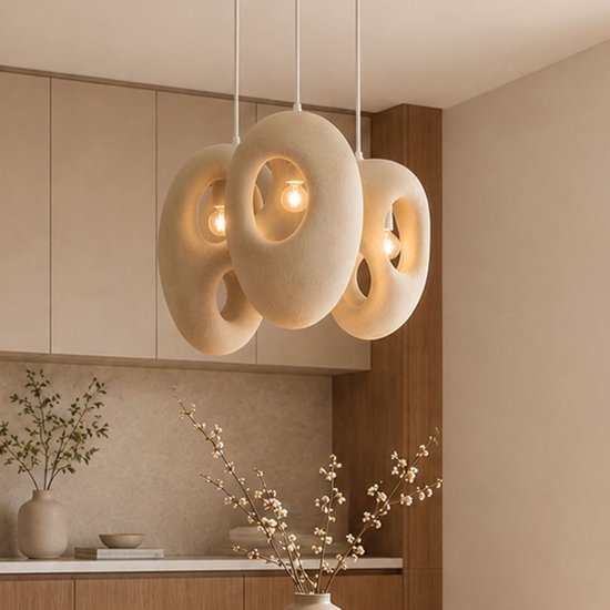 Drie beige, steenlook lampenkappen met organische vormen in een eetkamer met houten kasten.