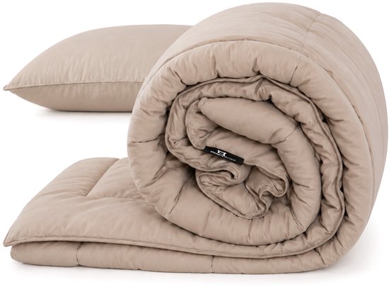 Een taupe dekbed en kussen zijn opgerold op een witte ondergrond.