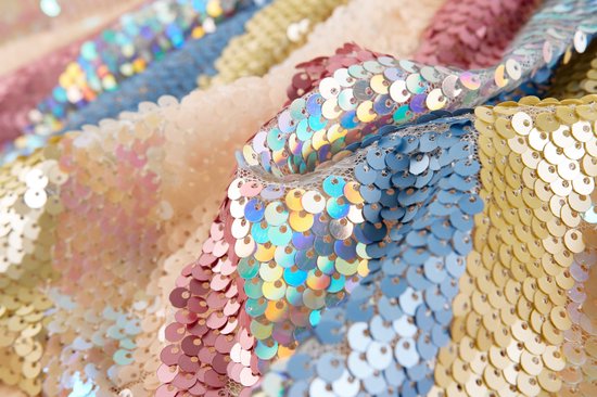 Gedetailleerde close-up van pailletten in de kleuren crème, roze, blauw en goud, gerangschikt in horizontale banen.