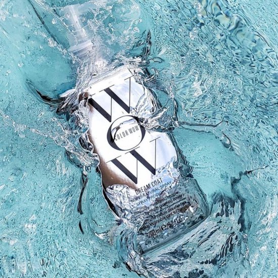 Zilverkleurige fles "DREAM COAT SUPERNATURAL SPRAY" in verfrissend blauw water, met splash.