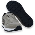 Beige sneaker met witte zool en zwarte rubberen loopzool. Een losse zool is zichtbaar.