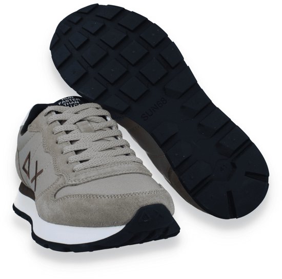 Beige sneaker met witte zool en zwarte rubberen loopzool. Een losse zool is zichtbaar.