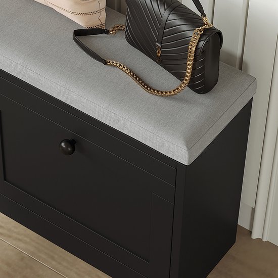 Detail van zwarte schoenenkast met grijze zitting, handtas en hoge hakken.