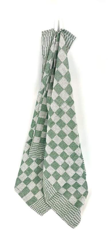 Un torchon vert à carreaux suspendu sur un fond blanc.