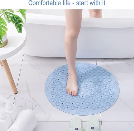 Een voet stapt op een lichtblauwe, ronde antislip douchemat in een moderne badkamer. De mat heeft een patroon van zuignappen.
