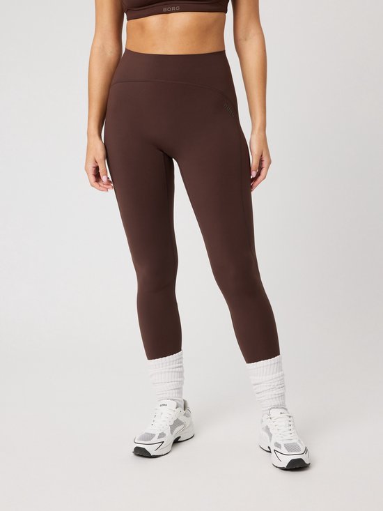 Vrouw in bruine sportlegging met witte sokken en sportschoenen.