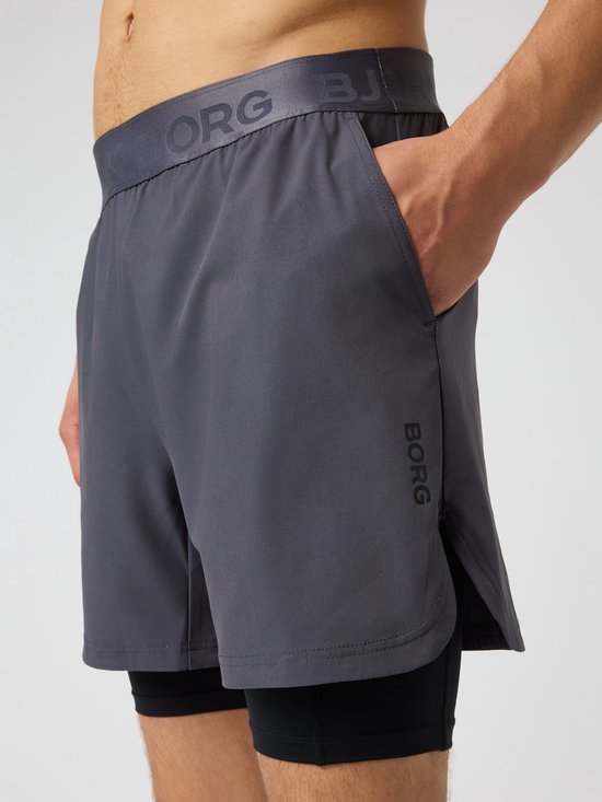 Gedetailleerd beeld van een donkergrijs trainingsshort met zwarte tight. Björn Borg logo op de tailleband.