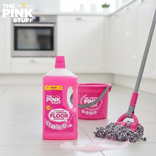 Fles The Pink Stuff vloerreiniger en een roze emmer met mop in een lichte keuken.