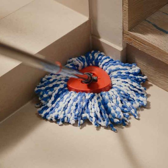 Spinmopkop met rode houder, witte en blauwe vezels, op een lichte vloer bij een hoek.