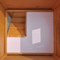 Binnenkant van een houten konijnenhok met witte wand en houten trap.