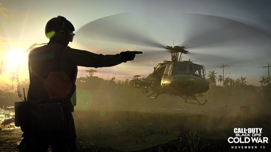 Soldaat wijst naar een helikopter bij zonsondergang, met tropisch landschap en gebouwen.