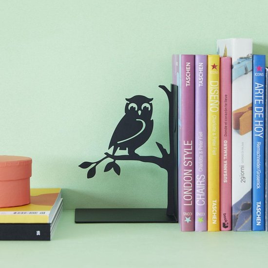 Zwarte boekensteun met uil op tak, naast boeken en een oranje doosje.