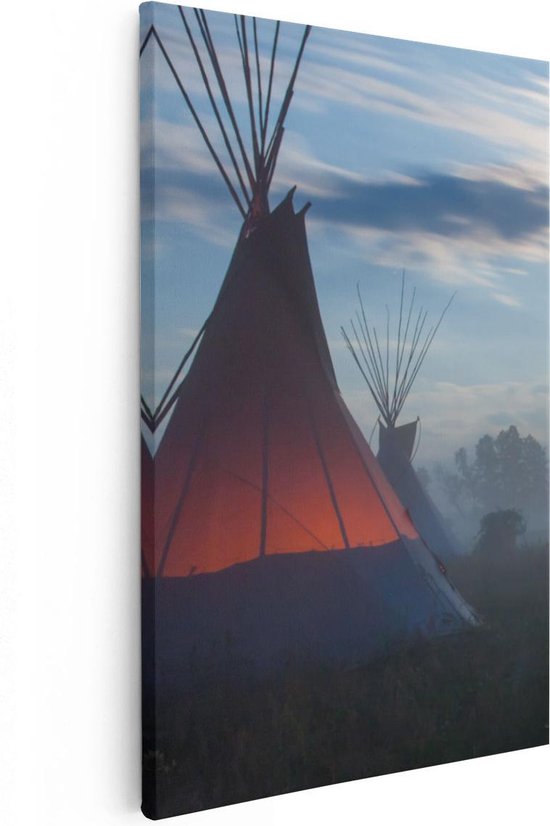 Deux tipis la nuit avec une lueur orange dans la brume, sur un ciel bleu avec des nuages.