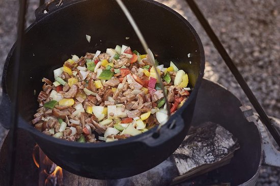 Gietijzeren pan met een mengsel van gesneden worst, paprika en andere groenten.