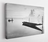 Canvas schilderij - Black and white scene of a traditional fishing boat in Tumpat, Malaysia, with the silhouette of the fisherman standing on the boat. Soft focus due to long expos