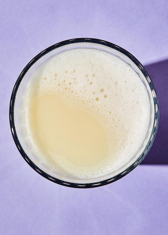 Bovenaanzicht van een glas met lichtgekleurde, schuimige drank.