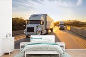 Behang - Fotobehang Twee vrachtwagens met een zonsondergang - Breedte 420 cm x hoogte 280 cm