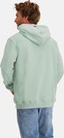 Achteraanzicht van een man in mintgroene hoodie en jeans op witte achtergrond.