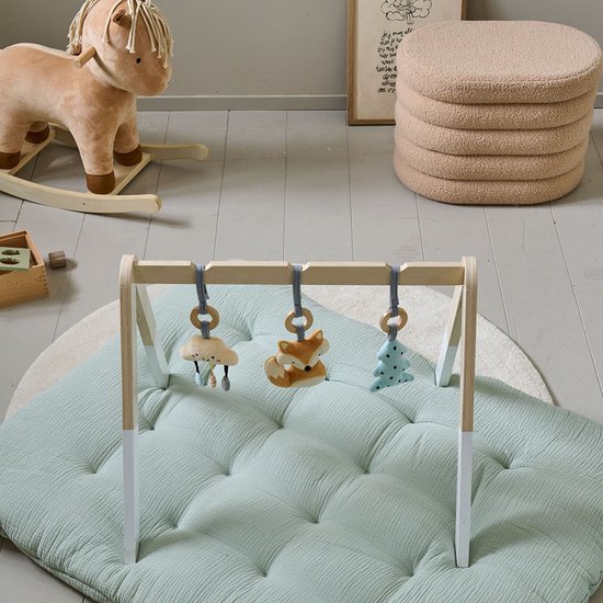 Lichtgroene speelmat met babygym en hangend speelgoed.