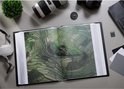 Open album op tafel met drone, camera en lens. Toont foto van groene rijstterrassen.