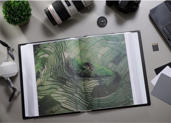 Open album op tafel met drone, camera en lens. Toont foto van groene rijstterrassen.
