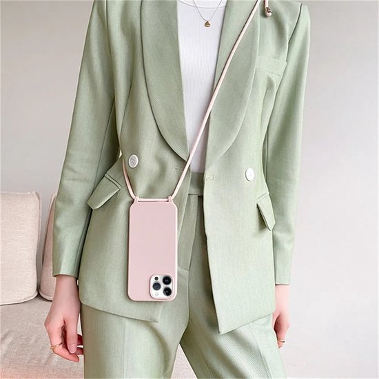 Model draagt een roze telefoonhoesje met koord over een lichtgroen mantelpak.
