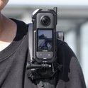 Zwarte Ulanzi C-X3 metalen cage voor Insta360 X3, bevestigd aan een schouderband. Met zichtbaar scherm.