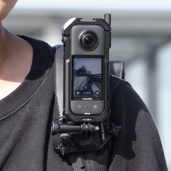 Zwarte Ulanzi C-X3 metalen cage voor Insta360 X3, bevestigd aan een schouderband. Met zichtbaar scherm.