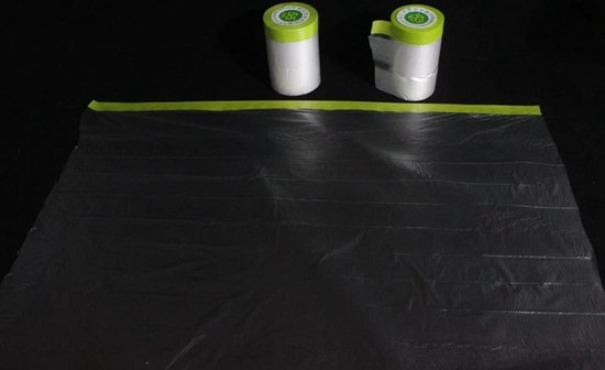 Twee rollen afplakfolie met groen afplaktape en een uitgerolde zwarte folie.