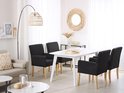 Salle à manger avec quatre chaises gris foncé, table blanche et un canapé beige.