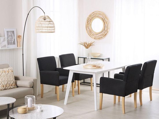 Salle à manger avec quatre chaises gris foncé, table blanche et un canapé beige.