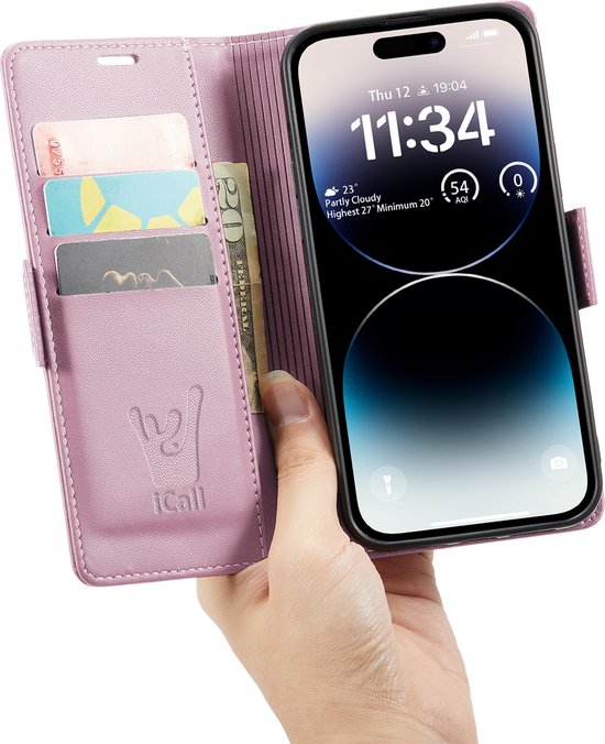 Une main tient un étui portefeuille rose en similicuir, style livre, ouvert, avec fentes pour cartes et un téléphone.