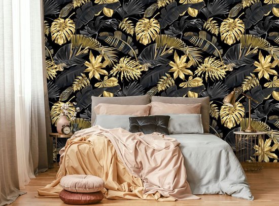 Gouden en zwarte jungle bladeren op een zwart behang. Bed met veel kussens en dekens.