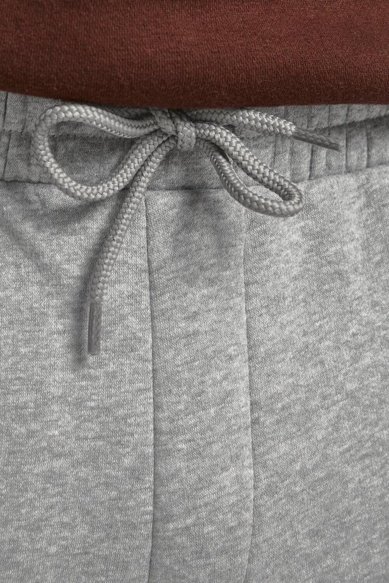 Sluit detail van de strik van het trekkoord van een lichtgrijze joggingbroek.