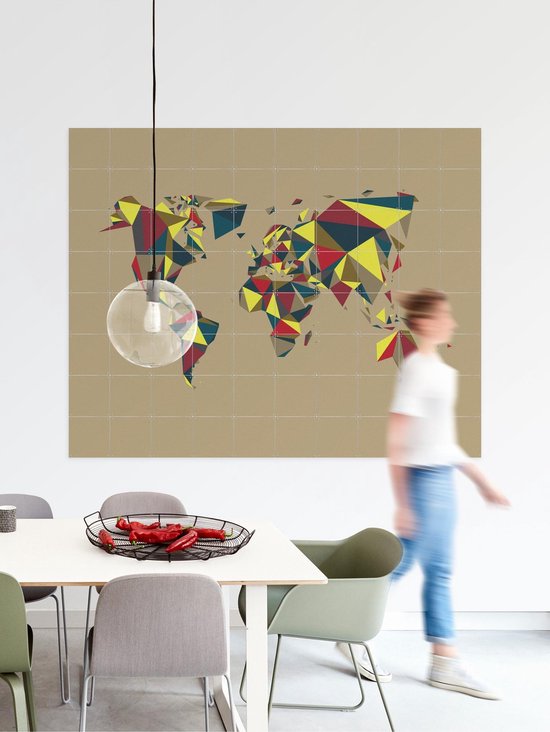 Carte du monde abstraite aux formes géométriques multicolores, accrochée dans une salle à manger où une femme passe.