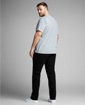 Man met donkere huidskleur draagt een grijze t-shirt en zwarte jeans, achterkant.