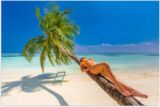 Poster Glanzend – Vrouw in Gele Bikini Liggend op Schuingroeiende Palmboom op Tropisch Strand - 60x40 cm Foto op Posterpapier met Glanzende Afwerking