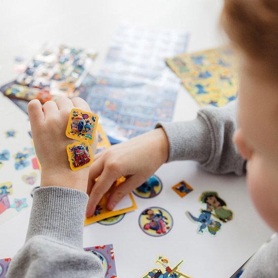 Un enfant colle des autocollants Stitch sur sa main. D'autres autocollants Stitch sont sur la table.