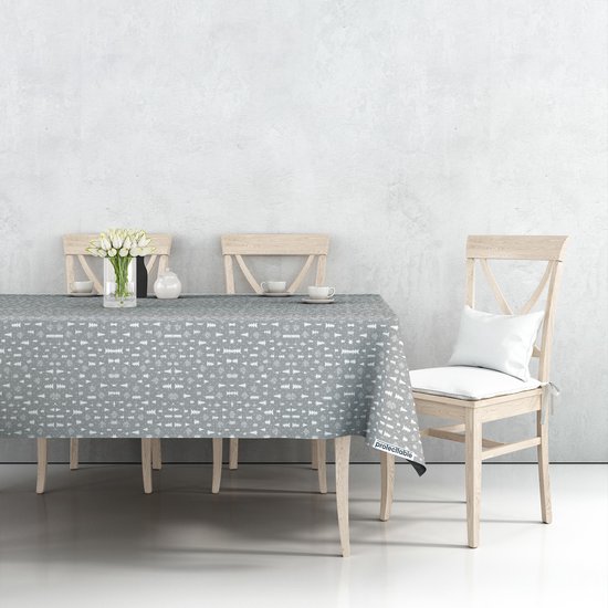 Nappe grise à motif d'arbres de Noël, dressée sur une table de salle à manger avec des tulipes blanches et des chaises.