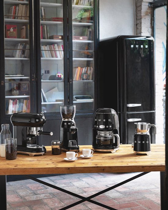 Zwarte SMEG keukenapparatuur: espressomachine, koffiemolen, koffiezetapparaat en koelkast.