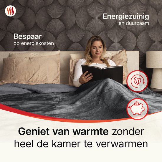 Vrouw leest boek onder een grijze elektrische deken, bespaart op energiekosten. Geniet van warmte zonder de hele kamer te verwarmen.