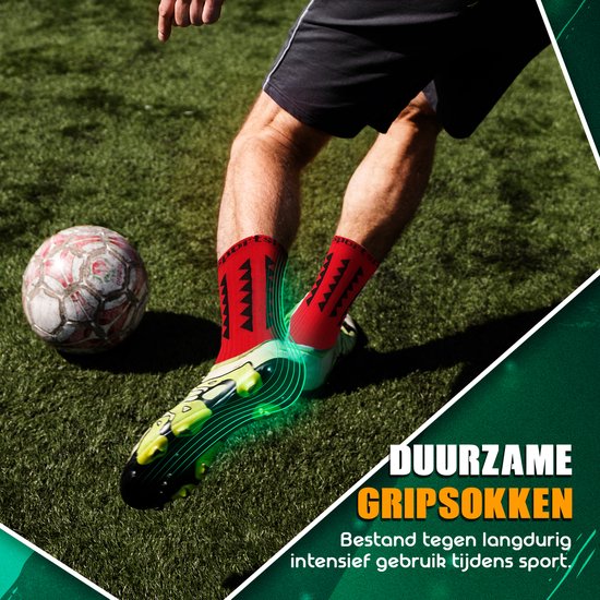 Pied dans une chaussette de sport rouge avec picots antidérapants et une chaussure de football, jouant au football sur de l'herbe verte.