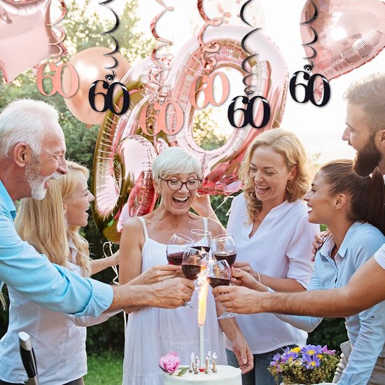 Groep lacht en heft glazen bij een verjaardagstaart met grote '60' ballonnen in rosegoud.