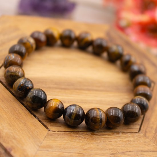 Armband van bruine en gouden tijgeroog kralen op een houten standaard.