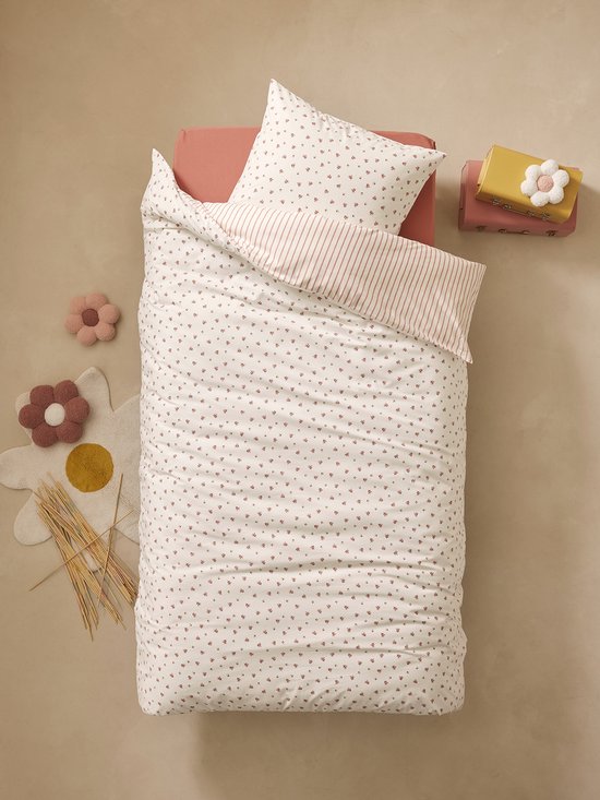 Bed opgemaakt met een dekbedovertrek met kleine roze bloemetjes en een gestreept kussensloop.