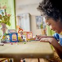 Enfant jouant avec le magasin de vêtements vintage LEGO Friends sur une table en bois.