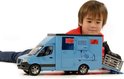 Lichtblauwe Bruder paardenwagen met een jongen die ernaar kijkt. Een paard staat op de laadklep.