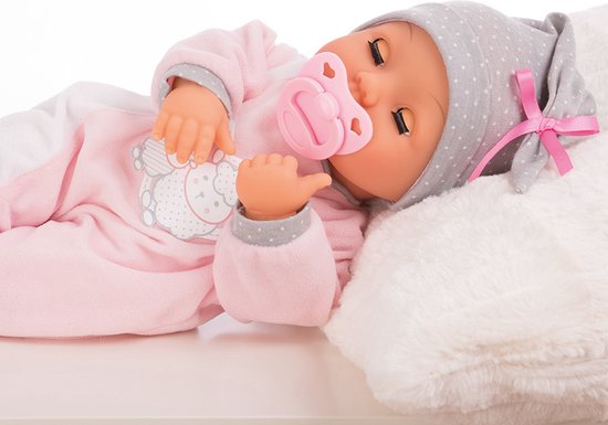 Slapende babypop in roze slaappakje met grijze stippenmuts, liggend op een kussen.