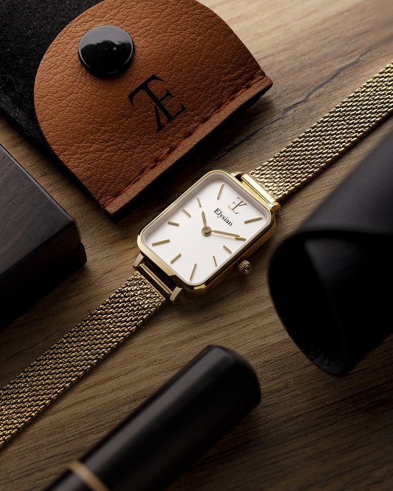 Gouden rechthoekig horloge met mesh band, omringd door bruine leren etui en zwarte accessoires op hout.