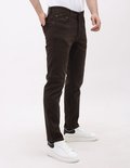 Man in bruine regular fit jeans met witte sneakers, rechterhand in de zak.